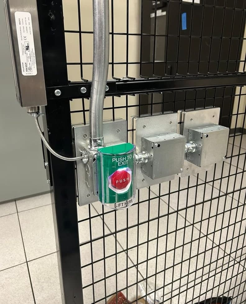 Before and after: open junction boxes and loose wiring on a mesh cage door, then a maglock on the frame and a green push-to-exit button under a clear cover, with the boxes closed.