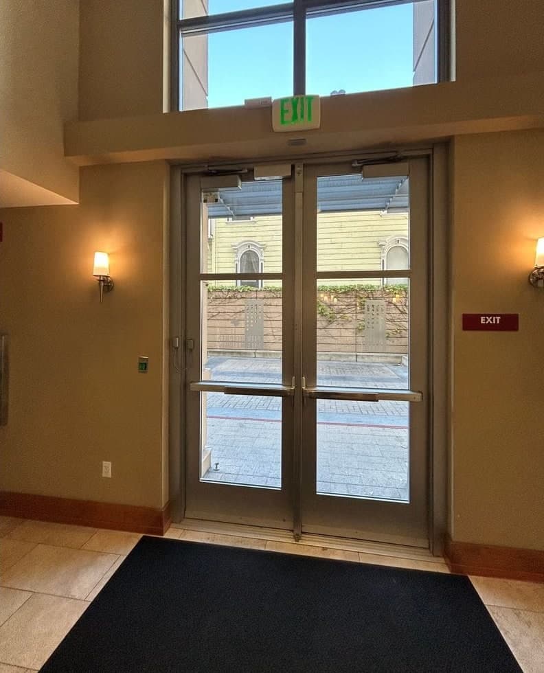 Before and after: glass double doors in a lobby with a blank wall plate, then the same doors with a magnetic lock (maglock) at the header and a green push-to-exit button beside them.