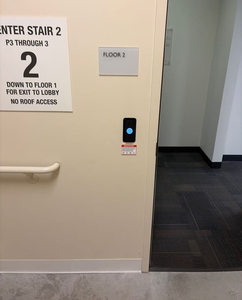 Before and after: an older rectangular reader beside a stairwell opening, then a Kisi reader at the same mounting spot.