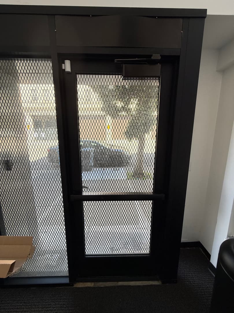 Commercial interior entry with a surface door closer and exit hardware.