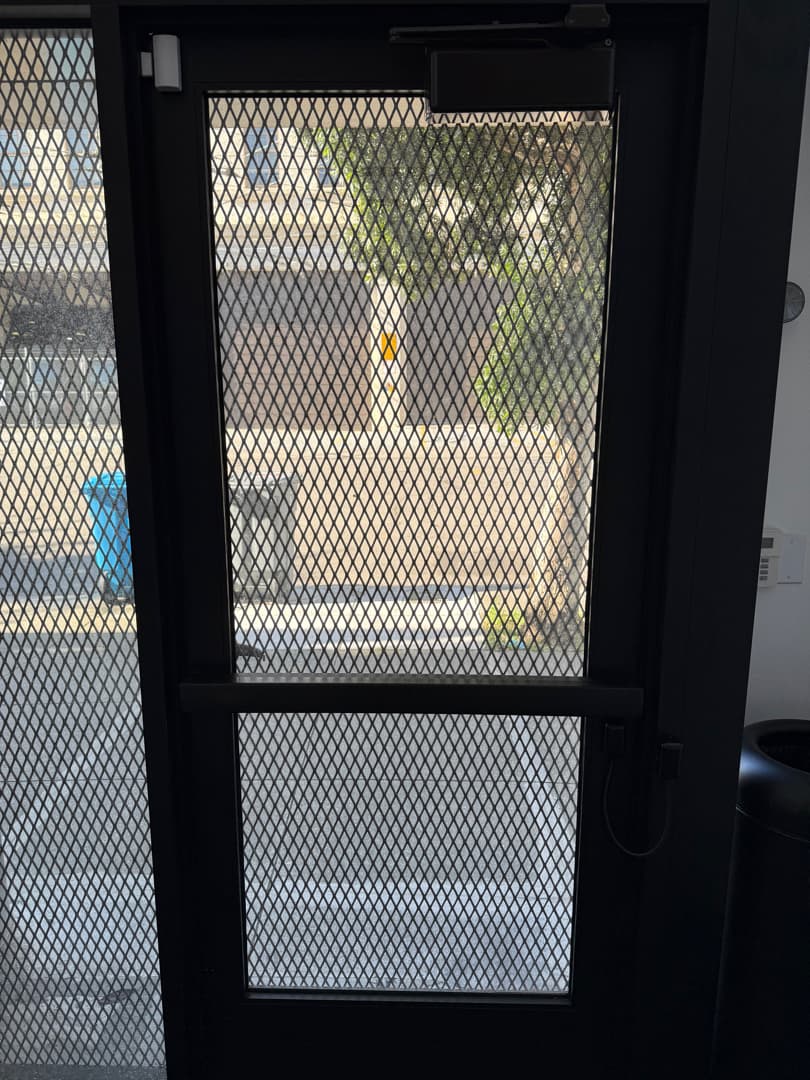 Low-voltage door release hardware detail at a Bay Area commercial opening.