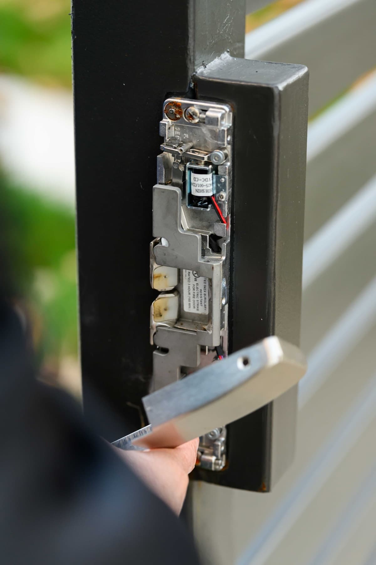 Close-up of an electric strike's exposed internals with an Elwin technician holding the cover plate.