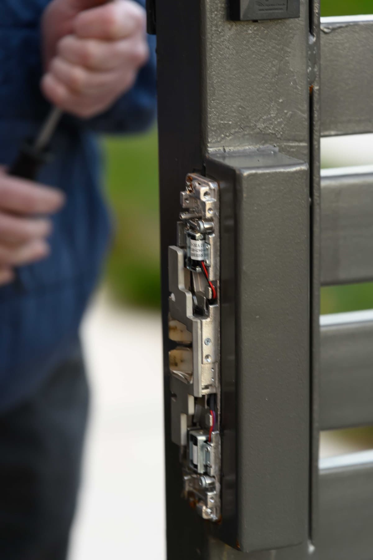 Exposed electrified latch mechanism with solenoid and wiring at a Bay Area gate serviced by Elwin.