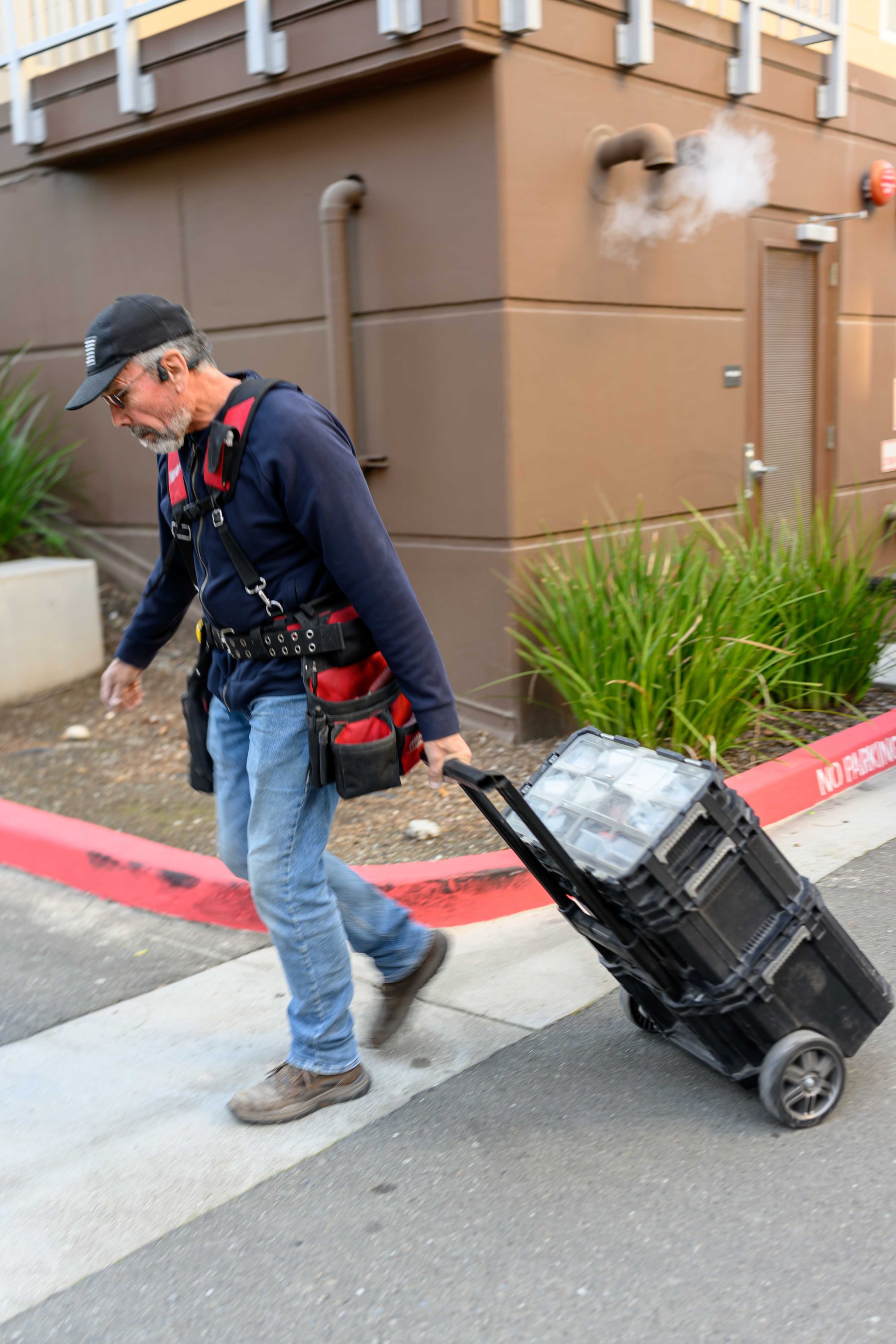 Technician moving service tools across a Bay Area property walkway.